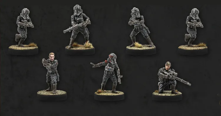 Seven miniatures are displayed against a dark background, showcasing the Imperial Special Forces from Star Wars: Legion. The figures include various troopers in tactical gear, some holding blasters and others in dynamic poses, with details like helmets and insignia visible. The bases are textured with grass, adding to the realistic appearance of the miniatures.