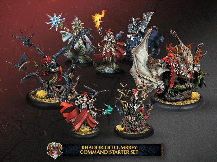 A collection of intricately designed miniatures from the Khador Old Umbrey Command Starter Set is displayed against a dark background. The set features several characters, including a witch with a fiery hand, a cloaked figure wielding a staff, and a fierce warbeast resembling a dragon. The miniatures are detailed with vibrant colors and textures, showcasing elements like flowing robes, twisted branches, and mystical symbols, all set on bases adorned with grass and stones. A banner at the bottom identifies the set as the 