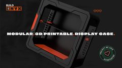 A sleek, 3D-printable display case designed for collectors, featuring a black exterior with angular lines and a vibrant red base. The case is shown from a slightly elevated angle, highlighting its modular design and snap-fit assembly, which requires no tools. The text "3D-PRINTABLE. DISPLAY CASE." is prominently displayed, along with a "PROJECT WE LOVE" badge from Kickstarter.
