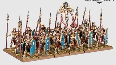 Miniature models of six skeleton chariots with detailed Nehekharan designs, each pulled by two skeletal horses. Chariots carry two skeletal warriors with spears and shields. Background shows skeletal warriors and archers in varied poses, some holding spears, others bows.