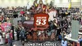 A bustling scene from SALUTE 53, Europe's largest independent wargames show, held at the London ExCel. The image captures a crowded exhibition hall filled with attendees exploring various vendor stands, with a prominent graphic overlay featuring the event's logo and artwork of a knight, a horse, and other characters. The atmosphere is lively, showcasing the excitement and engagement of the wargaming community.