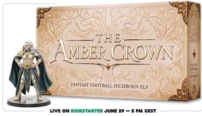 Ornate gold and cream-colored plaque with intricate vine and leaf embellishments framing the text. The plaque reads: "THE AMBER CROWN FANTASY FOOTBALL HIGHBORN ELF." A small, faceted amber-colored gem is embedded near the center. Below the plaque, part of a person's leg is visible, wearing blue jeans and a black sneaker. At the bottom of the image, green text on a black background reads: "LIVE ON KICKSTARTER JUNE 29 — 5 PM CEST."