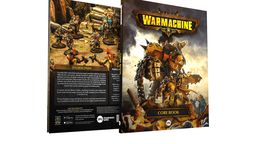 A hardcover rulebook for Warmachine is prominently displayed, featuring a striking cover with a large, armored warjack on the front. The back cover showcases a group of detailed miniatures in a rocky terrain, depicting various warcasters and constructs engaged in battle. Text highlights the core themes of the game, including its rich lore and the ongoing conflict in the Iron Kingdoms, while the spine of the book is labeled "CORE BOOK."