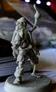A detailed miniature of a skeleton pirate stands with one arm raised, holding a round object, possibly a cannonball or a drink. The figure is intricately sculpted, showcasing skeletal features and pirate attire, including tattered clothing. The background is slightly blurred, revealing stacks of game-related materials, suggesting a tabletop gaming environment.