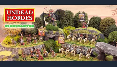 The scene features a vibrant tabletop display showcasing the "Undead Hordes" miniatures from Red Bard Games' Kickstarter campaign. In the foreground, a variety of skeletons and zombies are arranged on grassy terrain, with some holding banners and others in dynamic poses. A prominent liche king rides a zombie dragon atop a rocky outcrop, while additional figures, including a necromancer and various undead warriors, populate the scene, surrounded by lush greenery and stone formations. The overall composition exudes a classic fantasy aesthetic, emphasizing the theme of an undead army ready for battle.
