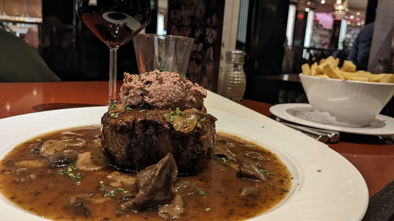 An aberdeen angus filet with duck confait in a red wine jus on a plate in a 1920s themed restaurant