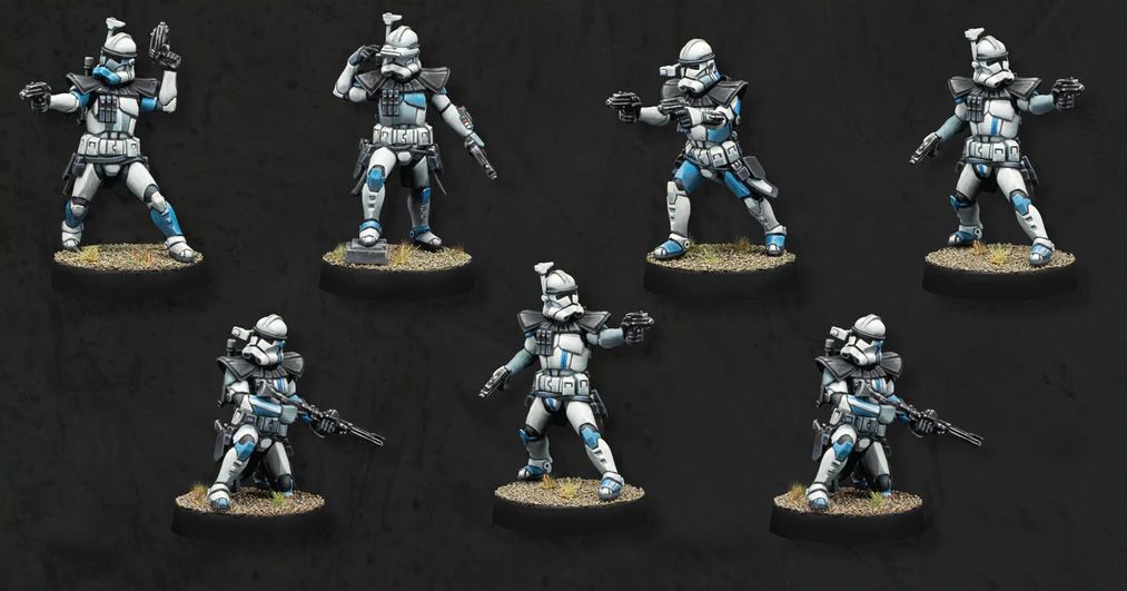 Seven Advanced Recon Commandos (ARC troopers) are depicted in the image, showcasing their distinctive white armor with blue accents. Each miniature is posed differently, some aiming weapons while others are in various stances, all standing on textured bases with a grassy appearance. The background is a solid black, emphasizing the details and colors of the troopers.