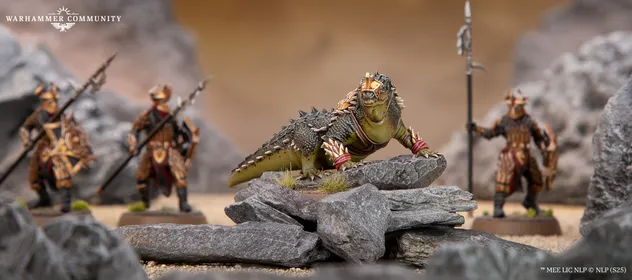 A fierce, green war drake with prominent spines and decorative armor stands atop a rocky outcrop, showcasing its detailed scales and menacing expression. In the background, an Easterling warrior clad in ornate armor holds a spear, partially obscured by rocks, emphasizing the drake's imposing presence. The scene is set against a blurred, sandy terrain, enhancing the focus on the miniatures.