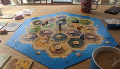 The Catan board laid out as  advised for beginners. On a dining table with tea