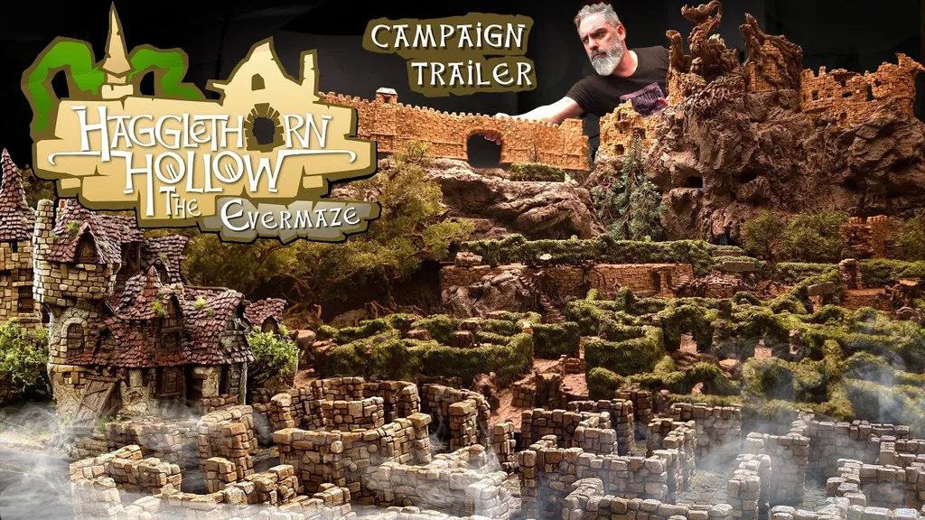Miniature fantasy landscape with stone castle ruins, winding hedge maze, and rocky terrain. A bearded man in a black shirt leans over the display. Text reads: "CAMPAIGN TRAILER" and "Hagglethorn Hollow."