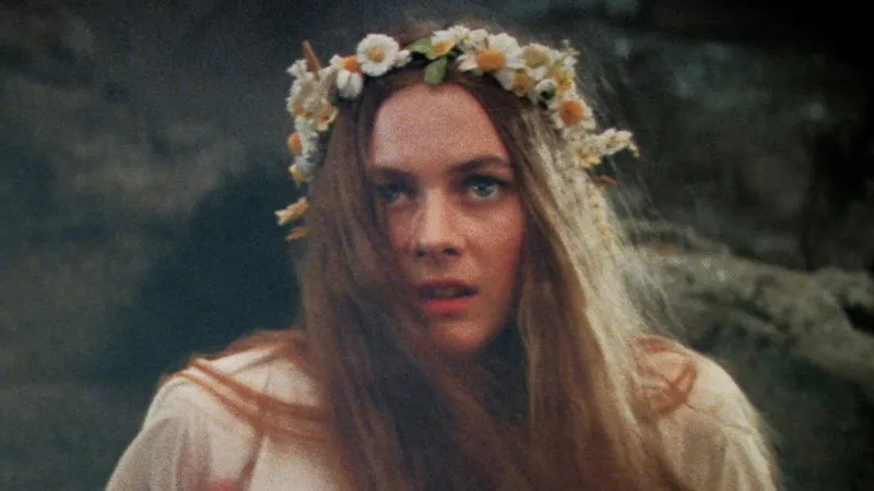 Woman with long blonde hair wearing a white and yellow flower crown.