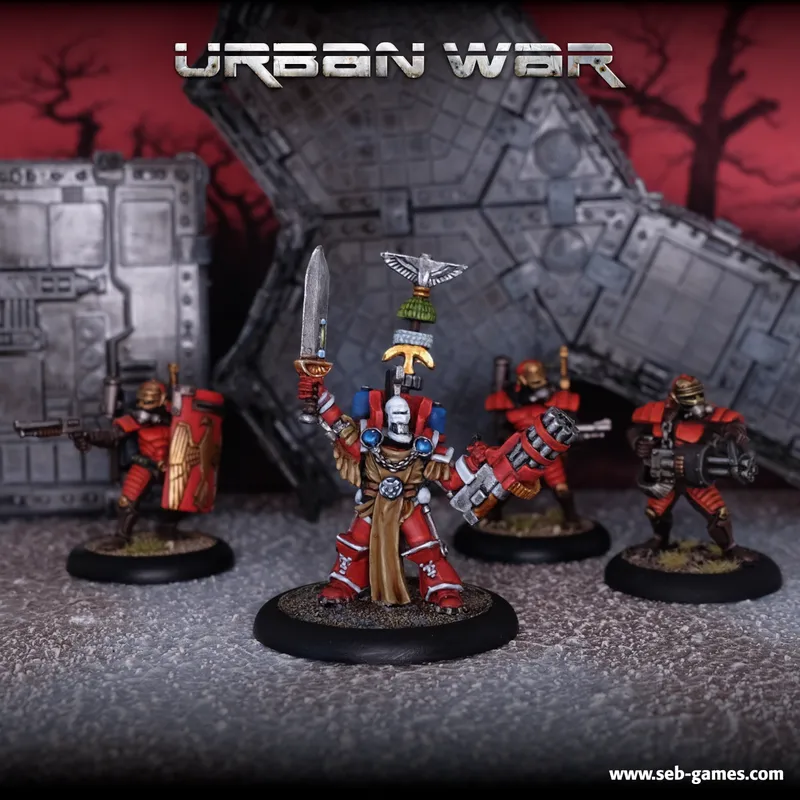 Four miniature figurines of armored soldiers stand on round black bases against a backdrop of gray, futuristic urban ruins. The background features angular, block-like structures resembling buildings with sharp, geometric patterns.

The central figurine wears ornate armor with red, white, and gold details, including a tall, decorative headdress with a winged emblem at the top. This figurine holds a long, curved sword raised in one hand and a small shield in the other.

To the left, a figurine in red armor with gold accents holds a rifle-like weapon aimed forward. To the right, two additional figurines in similar red armor with black and gold accents also hold rifle-like weapons aimed forward.

At the top of the image, the text "URBAN WAR" is displayed in large, metallic gold letters. In the bottom right corner, the website "www.seb-games.com" is visible in small white text.