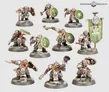 Nine miniature Khazalite duardin warriors in dynamic poses, wearing green-and-grey armor, helmets, and carrying round green shields with white symbols. One figure holds a green banner with a white emblem. All stand on rocky bases.