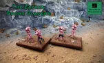 Three Zayken Spore Slaver miniatures are displayed on textured brown bases, set against a rocky backdrop. The miniatures are grotesque, with pinkish skin and bulbous heads featuring multiple eyes, emphasizing their monstrous appearance. The text "THE ZAYKEN SPORE SLAVERS" is prominently featured in green above the miniatures.