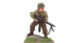 A 28mm scale miniature of a soldier, representing the war hero Audie Murphy, stands on a rocky base adorned with green grass. The figure is dressed in a light green military uniform with insignia on the sleeves and wears a helmet. He holds a machine gun in a ready position, showcasing a determined expression.