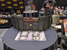 Model of Castle Ravenloft with miniatures on a map, WizKids banners in background.
