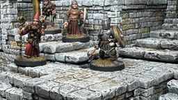 A detailed scene showcases a modular dungeon setup made from intricately sculpted stone blocks, featuring various levels and staircases. Four miniatures are positioned on the blocks: a bearded wizard with a staff, a robed figure holding a spear, and a knight in armor wielding a weapon, all engaged in exploration. The textured stone surfaces and the overall layout highlight the versatility of the dungeon blocks for tabletop gaming.