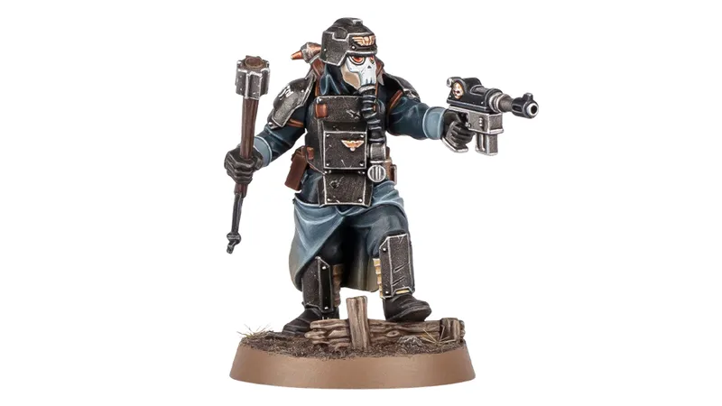 A detailed miniature figure of a Death Korps of Krieg Combat Engineer stands on a textured base, holding a hammer in one hand and a pistol in the other. The figure is dressed in dark, militaristic attire with a distinctive gas mask and helmet, featuring various armor plates and insignia. The base includes small wooden debris, enhancing the battlefield aesthetic.