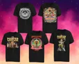 Six black T-shirts with fantasy-themed prints. Top row: "Hellcrawl" skull logo, "Weird Gulch" with cartoon monster and text. Bottom row: "The Painted Wastelands" with illustrated figure, "Deadlands" with skull and text, and "Madness" circular emblem.