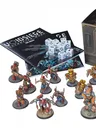 A collection of detailed resin miniatures from the Sythopian Wars starter set titled "VoidSiege" is displayed prominently. The scene includes various character models and units, such as the Asylumist N-Force and the Confederation forces, arranged around two copies of the 28-page rulebook and a set of dice. A box featuring futuristic design elements is also present, adding to the thematic presentation of the game.