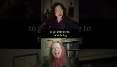 Two individuals are engaged in a lively conversation, with one person on the top half of the image and the other on the bottom. The person at the top has dark, wavy hair and is wearing glasses, while the person at the bottom has long, reddish hair and is also wearing glasses. The background features shelves filled with books and other items, suggesting a cozy, personal space. Subtitles appear on the screen, with the phrase "to get immune to the stabbing" prominently displayed, adding a humorous and intriguing context to their discussion.