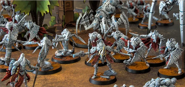 A detailed scene showcases a variety of intricately designed robot miniatures, each with a metallic silver and blue color scheme, set against a textured brown base. The figures include humanoid robots with flowing capes, armed with futuristic weapons, and larger mechanical constructs in the background. The composition highlights the diversity of the robot legions, emphasizing their advanced technology and battle-ready stance.