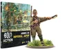 A book titled "Armies of Imperial Japan" from Warlord Games is prominently displayed, featuring a colorful cover illustration depicting Japanese soldiers in action, with a backdrop of explosions and military equipment. The book is positioned upright, showcasing its spine and cover, while a detailed 28mm miniature of a Japanese soldier is placed in the foreground, emphasizing the theme of the game. The text on the cover highlights the book's focus on World War II wargaming rules for the Imperial Japanese Army.