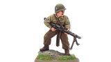 A 28mm scale miniature of a soldier, representing the war hero Audie Murphy, stands on a rocky base adorned with green grass. The figure is dressed in a light green military uniform with insignia on the sleeves and wears a helmet. He holds a machine gun in a ready position, showcasing a determined expression.