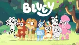 A colorful illustration features the characters from the children's cartoon "Bluey" standing together in a vibrant forest setting. The group includes Bluey, a blue heeler puppy, along with her family and friends, each characterized by distinct colors and patterns, such as a brown dog with a yellow shirt and a pink poodle. The title "BLUEY" is prominently displayed at the top in a playful font, enhancing the cheerful atmosphere of the scene.