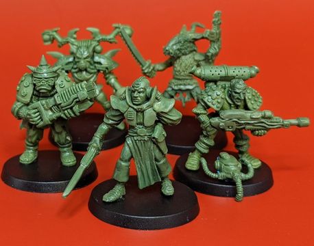 A group of five 28mm scale sci-fi miniatures is displayed against a bright red background. The figures include a Space Commando wielding a rifle, a Starchild with a distinctive helmet, an Assault Goar holding a sword, a Space Orc with a large gun, and a Voidborn equipped with various gadgets. Each miniature features intricate details and a classic old-school aesthetic, showcasing the unique character and charm of the RT Adventurer Pack II from Satyr Art Studios.