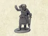 A grey resin miniature of the Master Fletcher stands on a circular base, depicted in a friendly pose with one hand raised in a gesture. He is dressed in a hooded cloak and tunic, with a quiver of arrows slung over his shoulder and a sword at his side. The background features a textured, light-colored surface that enhances the focus on the figure.